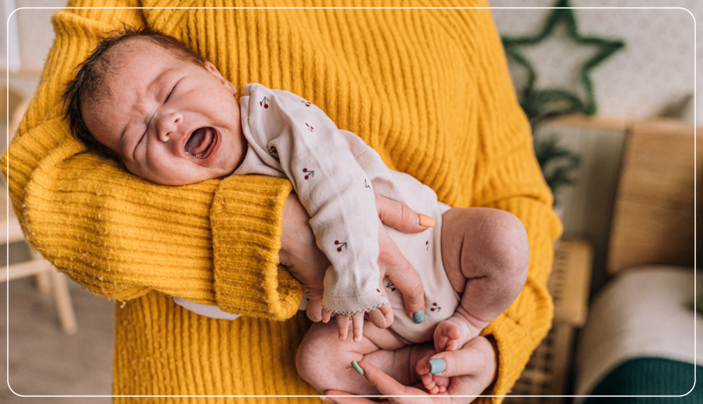 Gähnendes Neugeborenes auf dem Arm – Symbolbild für den Babybonus der Stadtwerke Schwarzenberg und die Entlastung, die er Eltern im stressigen Familienalltag schenkt