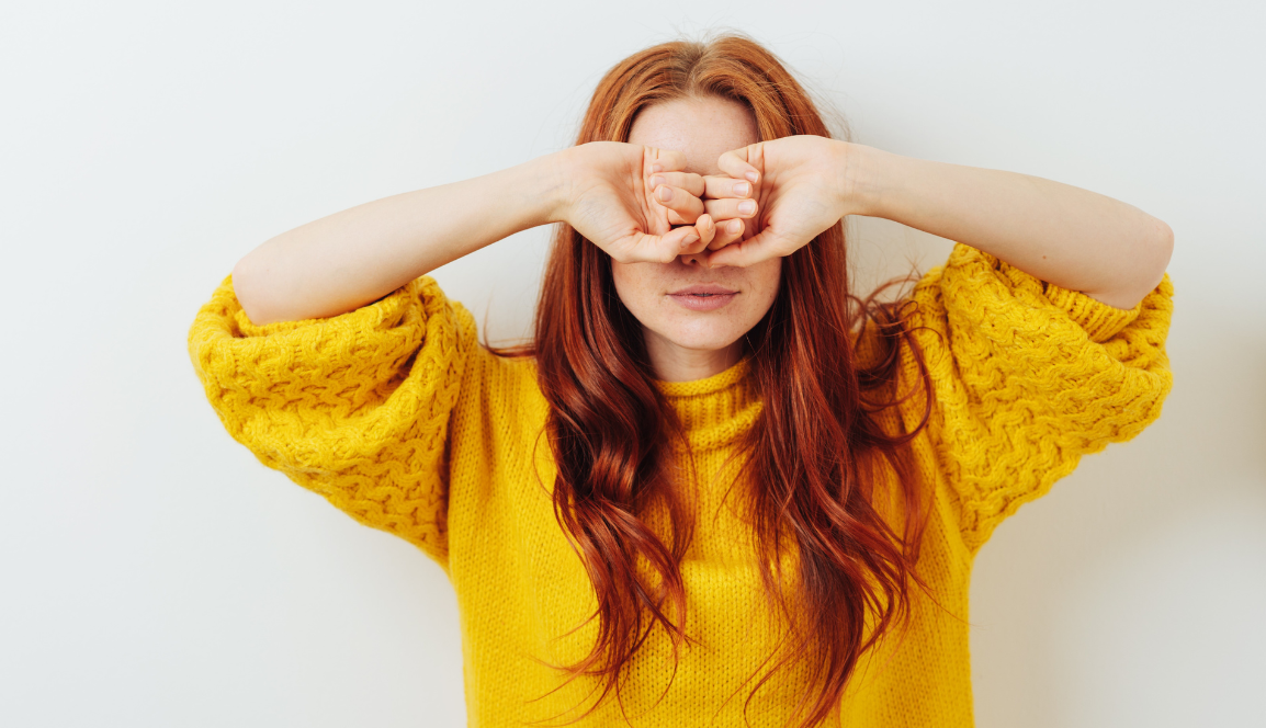 Eine Frau verdeckt sich nachdenklich die Augen – symbolisiert die Überlegung oder Unsicherheit, ob der Energievertrag gekündigt werden soll.