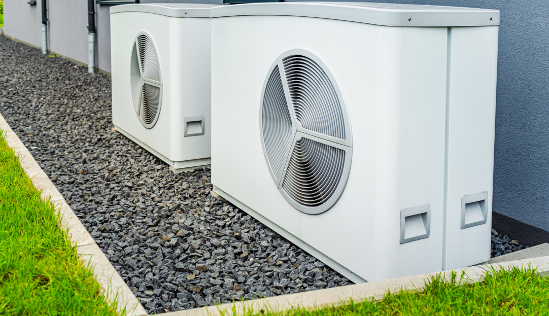 Eine Wärmepumpe steht im Garten eines Hauses – symbolisiert effizientes und umweltfreundliches Heizen mit speziell abgestimmtem Heizstromtarif.